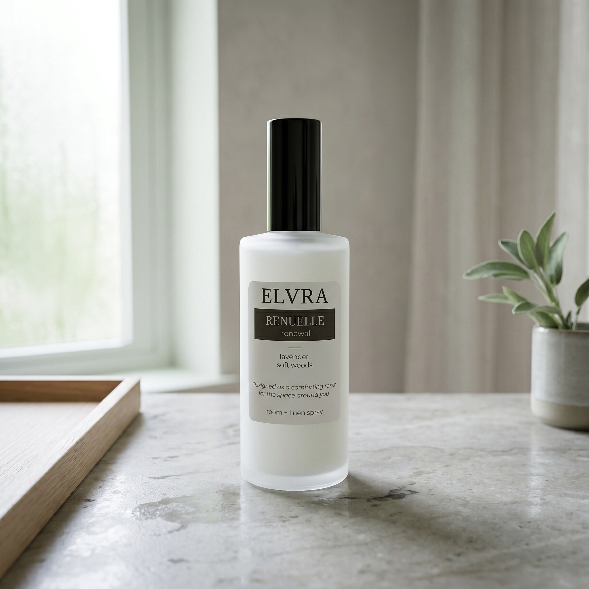 Frosted Elvra Renuelle Atmosphere and linen mist bottle on cool stone with soft daylight, pale wood, and a sage sprig nearby.