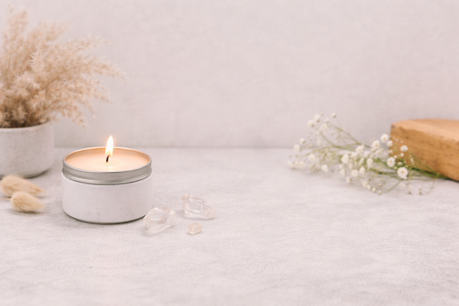 Candle in a tin container on a light surface with decorative elements