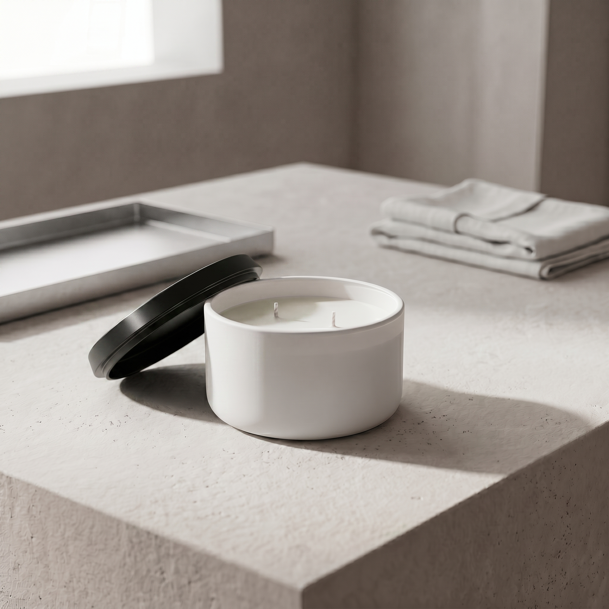 Elvra Klariti Minimal candle scene with a matte black metallic lid beside the white matte Candle, its slimmer profile catching a subtle edge highlight in soft studio light.