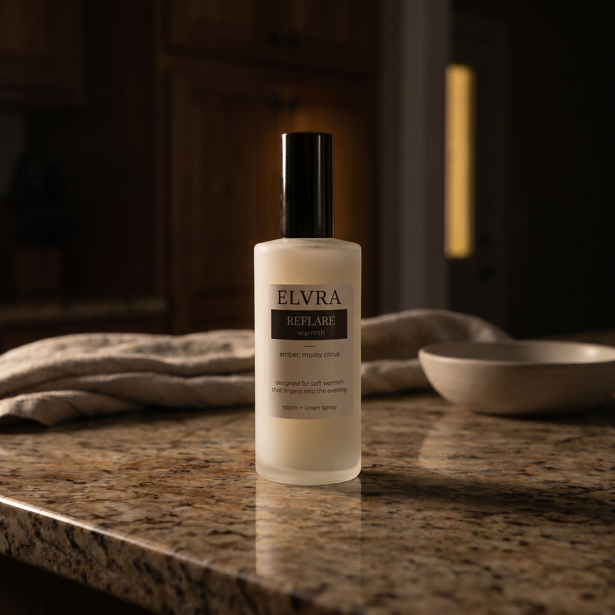 ELVRA Reflare Warmth Atmosphere mist bottle on warm stone with linen, oak, and soft amber evening light.